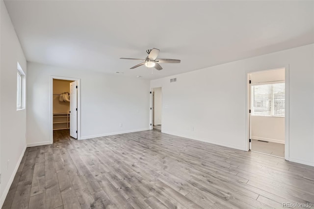 empty room with ceiling fan and light hardwood / wood-style flooring