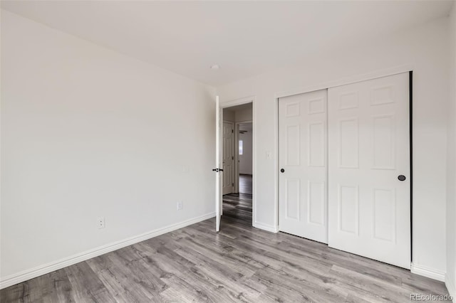 unfurnished bedroom with light wood-type flooring and a closet