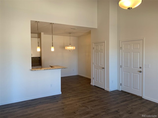 kitchen with dark hardwood / wood-style flooring, a notable chandelier, decorative light fixtures, and a towering ceiling