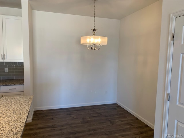 unfurnished dining area with dark wood-type flooring and a notable chandelier