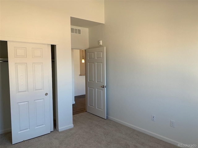 unfurnished bedroom with light colored carpet and a closet