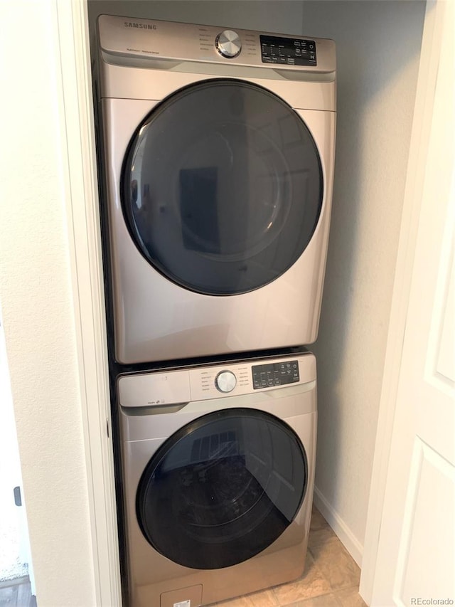 laundry area with stacked washing maching and dryer and light tile patterned floors