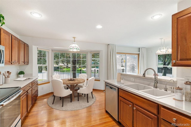 kitchen featuring pendant lighting, stainless steel appliances, light hardwood / wood-style floors, and sink