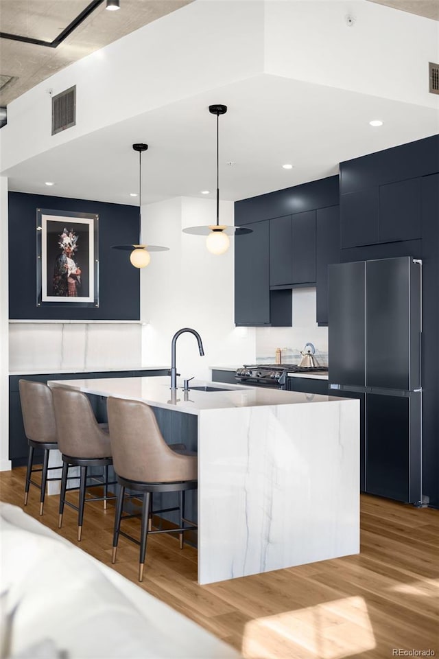 kitchen with a sink, modern cabinets, visible vents, and high end refrigerator