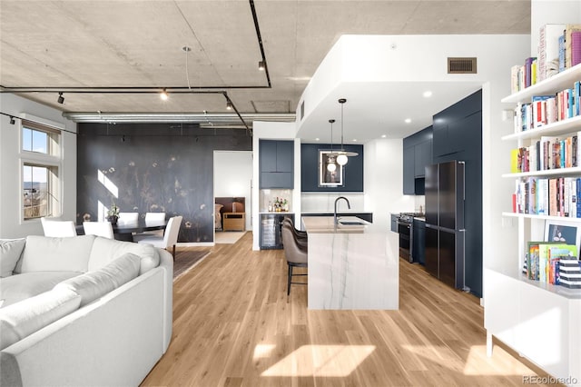 kitchen featuring a breakfast bar area, visible vents, a sink, light wood-style floors, and modern cabinets