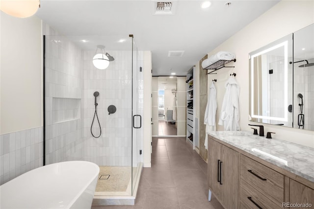 bathroom featuring tile patterned flooring, a spacious closet, visible vents, and a stall shower