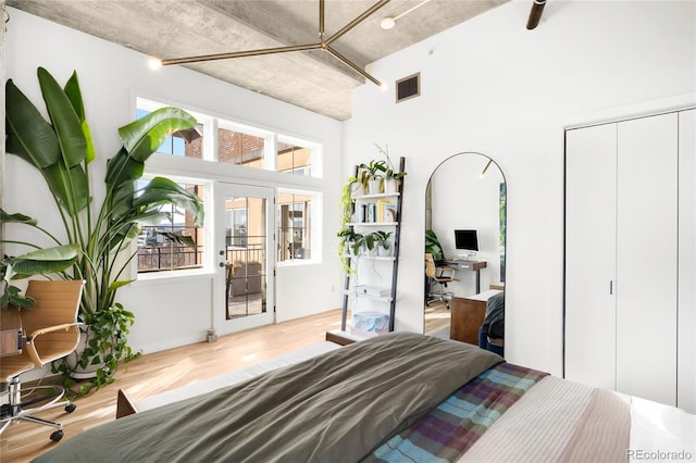 bedroom with a closet, visible vents, multiple windows, and wood finished floors