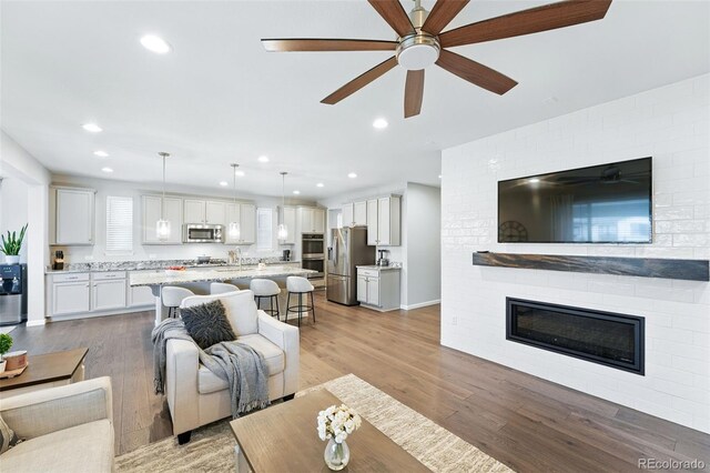 1101 E Witherspoon Dr, Elizabeth, CO 80107 - living room featuring a fireplace, light wood finished floors, a ceiling fan, and recessed lighting