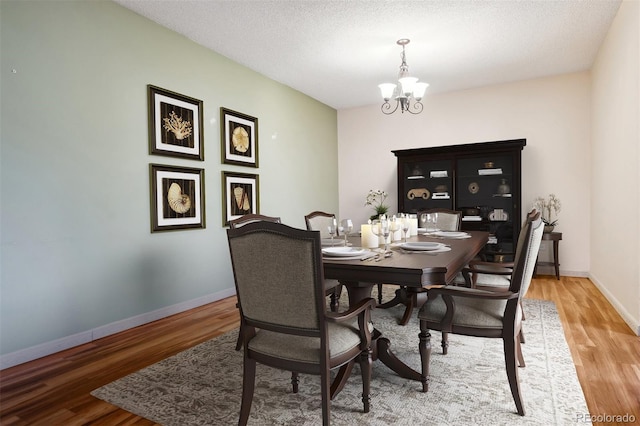 350 S Clinton St Unit 9C, Denver, CO 80247 - dining area featuring a chandelier, wood finished floors, baseboards, and a textured ceiling