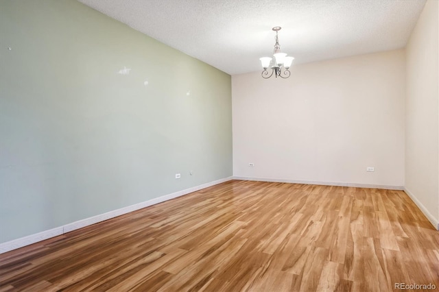 350 S Clinton St Unit 9C, Denver, CO 80247 - spare room featuring a chandelier, light wood-style floors, baseboards, and a textured ceiling