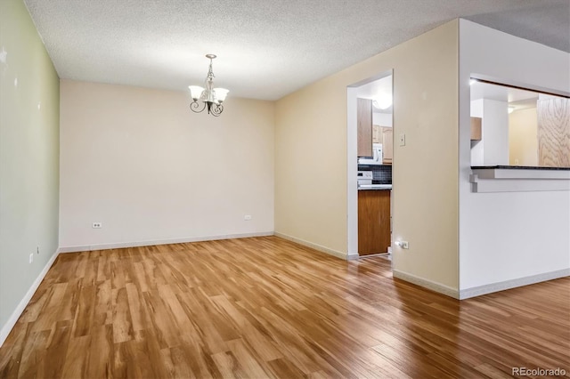 350 S Clinton St Unit 9C, Denver, CO 80247 - empty room with wood finished floors, a chandelier, baseboards, and a textured ceiling