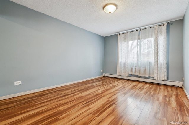 350 S Clinton St Unit 9C, Denver, CO 80247 - spare room with baseboard heating, wood finished floors, a textured ceiling, and baseboards