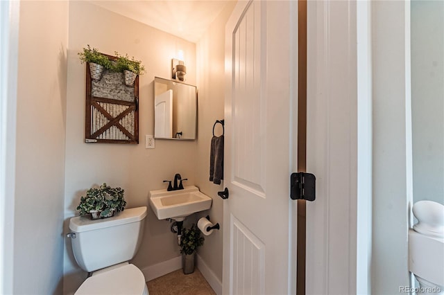 bathroom with toilet, a sink, baseboards, and tile patterned flooring