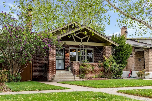 craftsman-style house with brick siding and a front yard