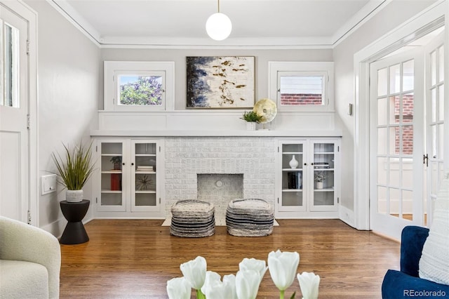 living room featuring ornamental molding, a brick fireplace, and wood finished floors