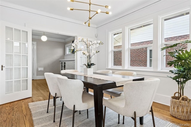 dining space with crown molding, light wood-style flooring, baseboards, and an inviting chandelier
