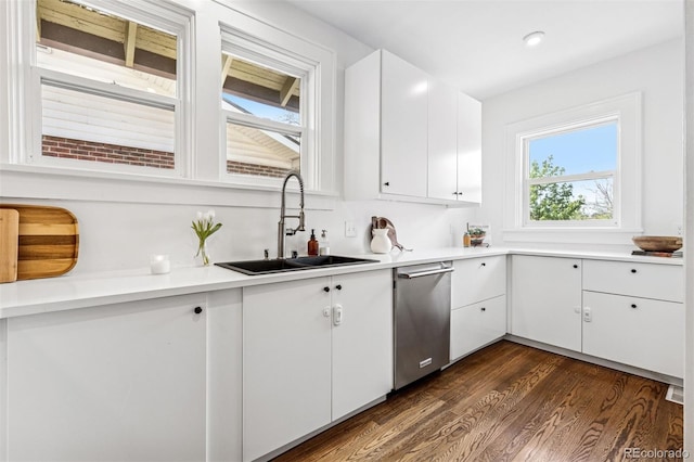 kitchen with a sink, white cabinets, stainless steel dishwasher, light countertops, and dark wood-style floors