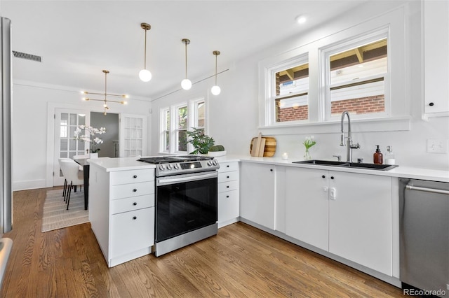 kitchen featuring a peninsula, a sink, white cabinetry, visible vents, and appliances with stainless steel finishes