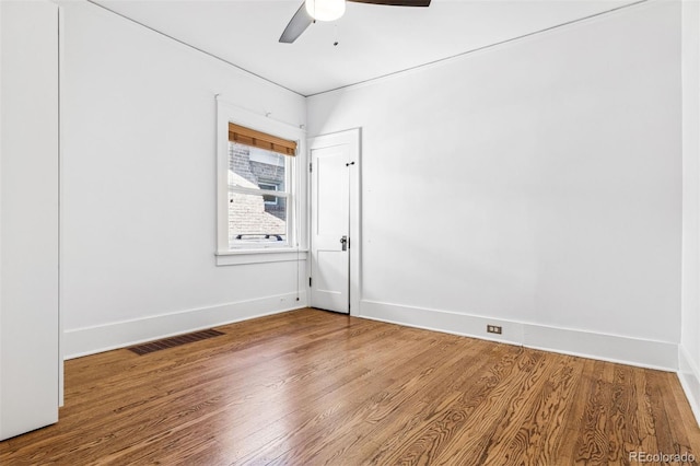 unfurnished room with ceiling fan, baseboards, visible vents, and wood finished floors