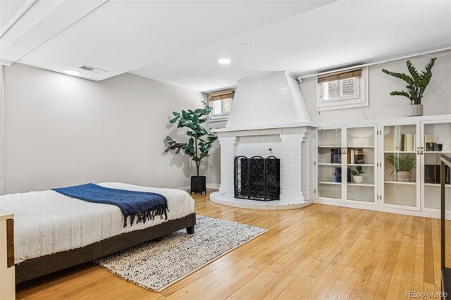 bedroom with recessed lighting, visible vents, a brick fireplace, and hardwood / wood-style flooring