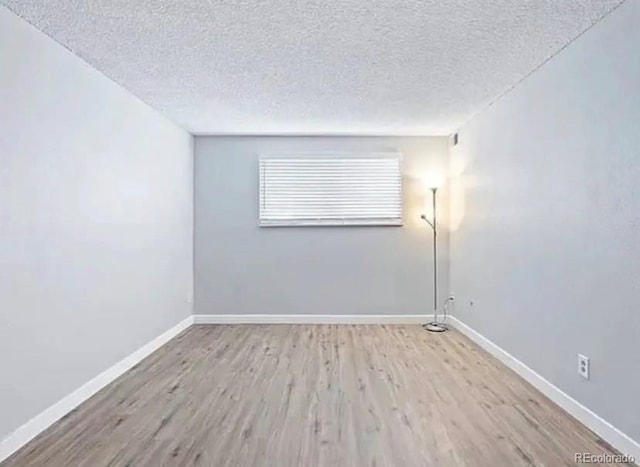 unfurnished room with light hardwood / wood-style flooring and a textured ceiling