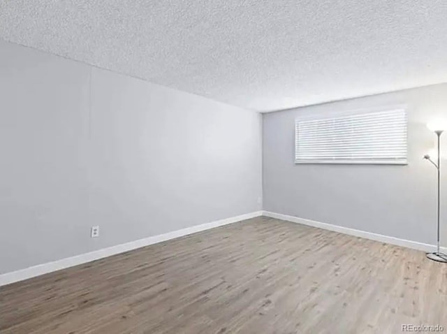 unfurnished room with a textured ceiling and light wood-type flooring