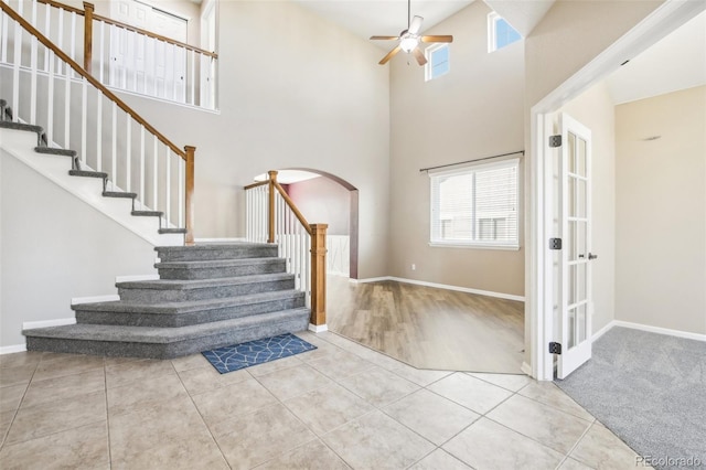 staircase featuring a towering ceiling, tile patterned flooring, and ceiling fan