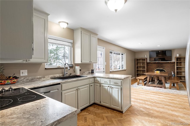 kitchen featuring sink, stainless steel dishwasher, kitchen peninsula, light parquet flooring, and a fireplace