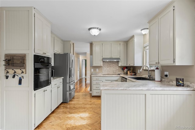 kitchen with black appliances, sink, white cabinets, light parquet floors, and kitchen peninsula