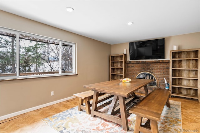 dining space featuring light parquet flooring and a fireplace