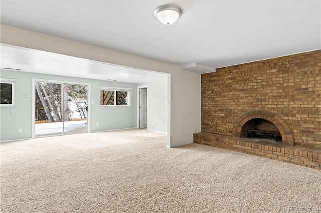 unfurnished living room featuring a brick fireplace and carpet