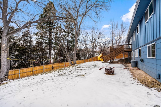 snowy yard with a wooden deck and an outdoor fire pit