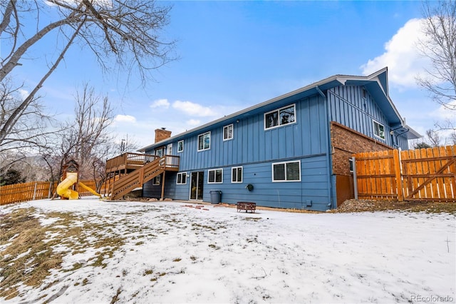 snow covered rear of property with a deck and an outdoor fire pit