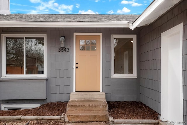 view of exterior entry featuring roof with shingles