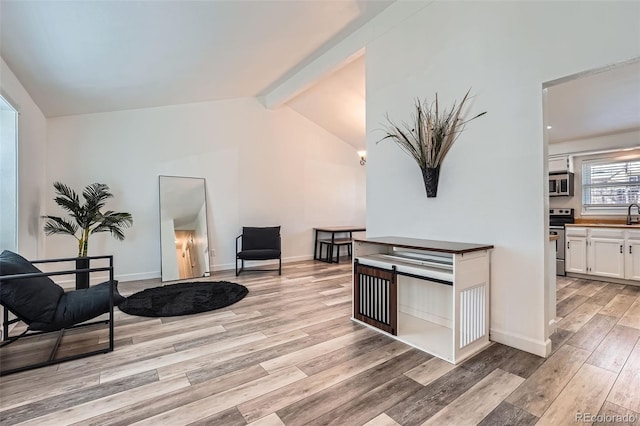 sitting room with lofted ceiling with beams, baseboards, and light wood-style floors