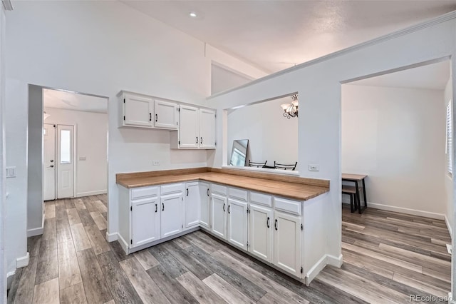 kitchen featuring baseboards, a notable chandelier, white cabinets, and light wood-style floors