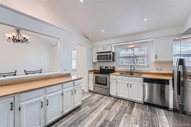 kitchen with stainless steel appliances, a sink, light countertops, and white cabinetry