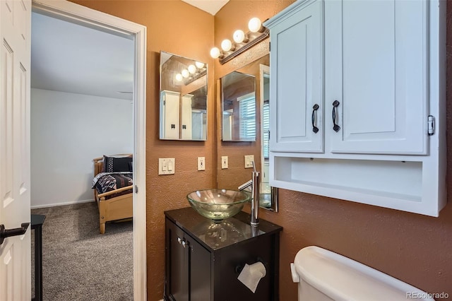 bathroom with a textured wall, vanity, and toilet