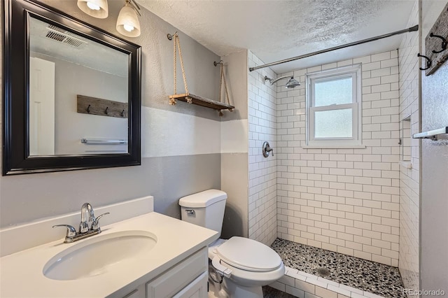 bathroom featuring visible vents, toilet, a shower stall, a textured ceiling, and vanity