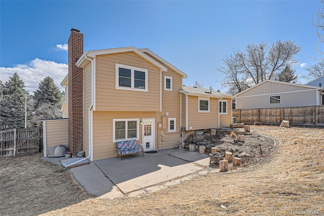 back of property with a chimney, a patio area, and a fenced backyard