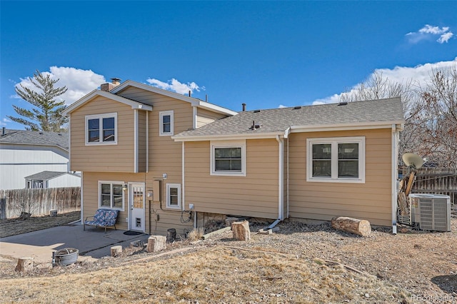 rear view of house with roof with shingles, fence, a patio, and central air condition unit