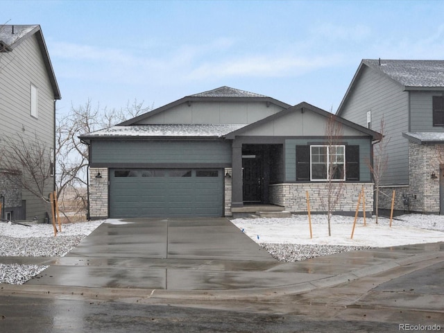 view of front facade featuring stone siding, an attached garage, and driveway