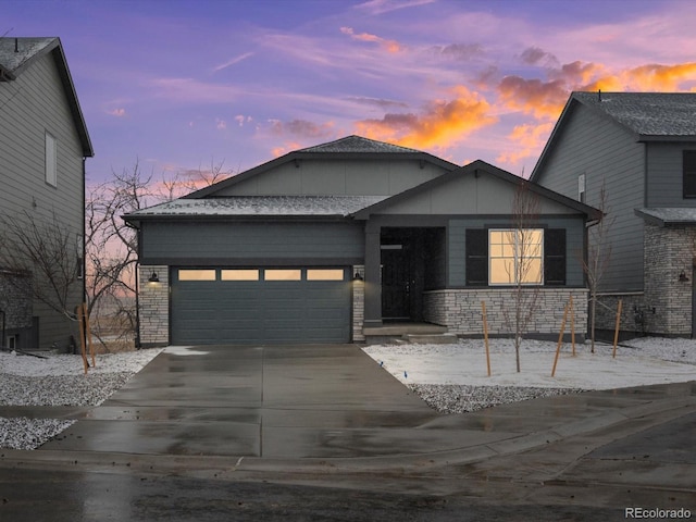 view of front of property with concrete driveway, an attached garage, and stone siding