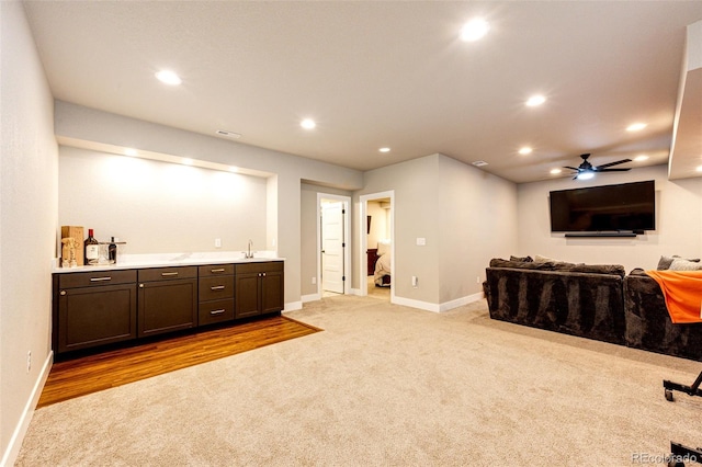 interior space with dark brown cabinetry, light colored carpet, sink, and ceiling fan