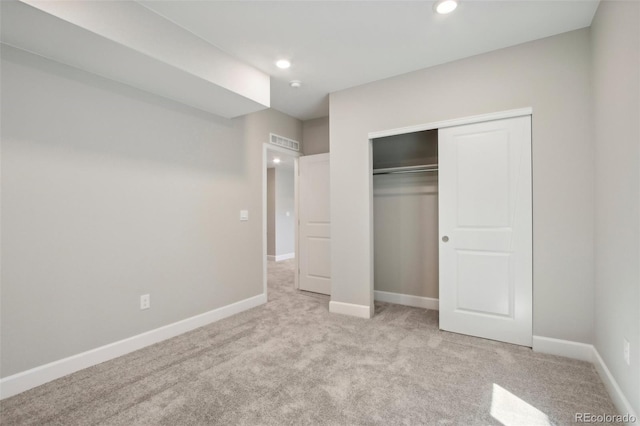 unfurnished bedroom with light colored carpet and a closet