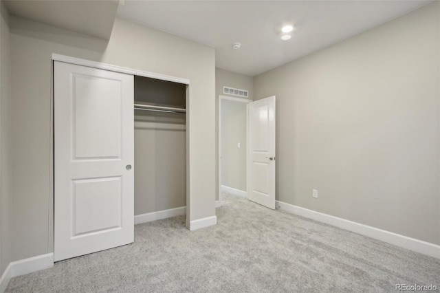 unfurnished bedroom with light colored carpet and a closet