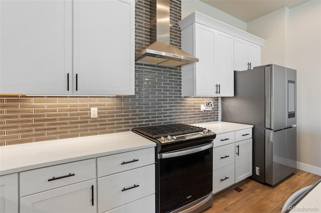 kitchen with wall chimney exhaust hood, appliances with stainless steel finishes, light countertops, and white cabinets