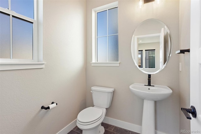 half bathroom with tile patterned floors, toilet, and baseboards