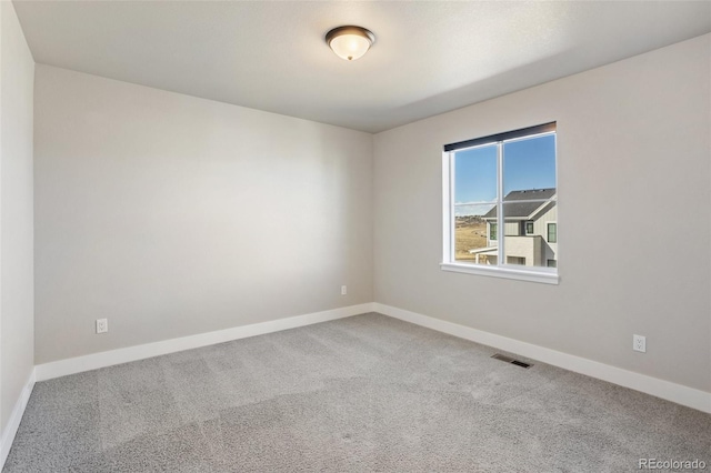 carpeted spare room featuring baseboards and visible vents