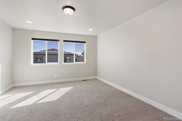 spare room featuring recessed lighting, light colored carpet, and baseboards